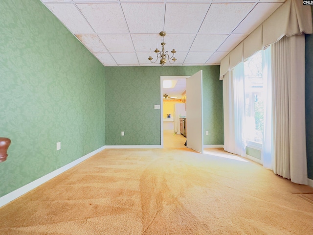 empty room with a drop ceiling, carpet floors, and a wealth of natural light