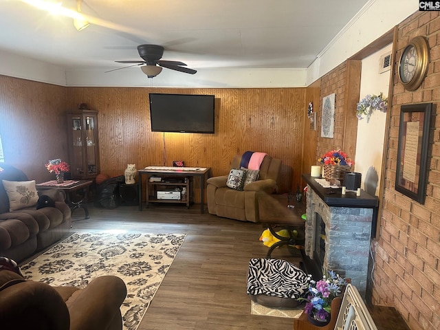 living room featuring ceiling fan, a fireplace, dark hardwood / wood-style flooring, and wood walls