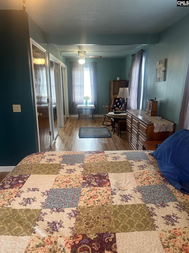 bedroom with ceiling fan, hardwood / wood-style flooring, and a textured ceiling