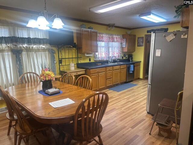 dining space featuring sink, crown molding, light hardwood / wood-style flooring, and a notable chandelier