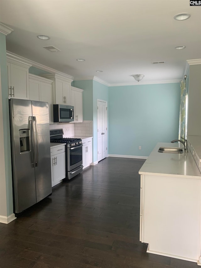 kitchen with decorative backsplash, white cabinetry, sink, and stainless steel appliances