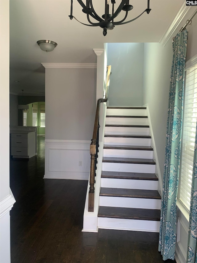 stairs with hardwood / wood-style floors, an inviting chandelier, and crown molding