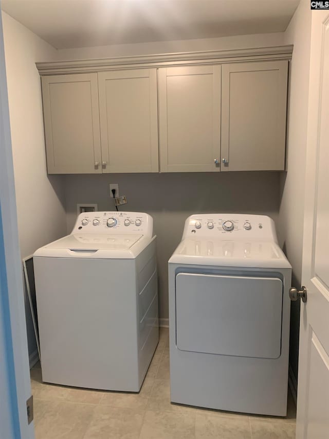 washroom featuring cabinets, light tile patterned floors, and washing machine and dryer