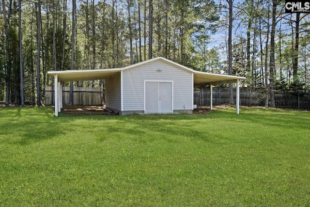 view of outdoor structure with a carport and a lawn