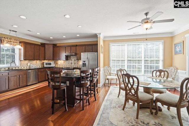 dining room with ceiling fan, a wealth of natural light, dark hardwood / wood-style flooring, and ornamental molding