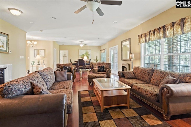 living room featuring ceiling fan with notable chandelier and dark hardwood / wood-style flooring