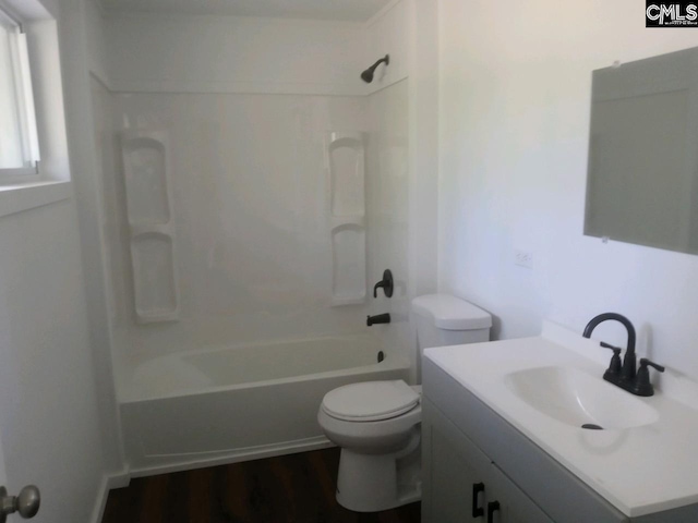 full bathroom featuring shower / bath combination, hardwood / wood-style flooring, vanity with extensive cabinet space, and toilet