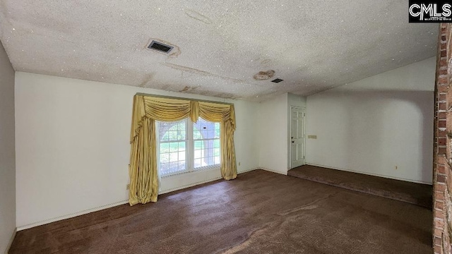 unfurnished room with brick wall, dark colored carpet, and a textured ceiling