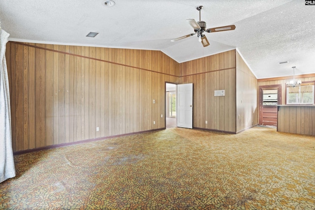 spare room with wooden walls, carpet floors, ceiling fan with notable chandelier, a textured ceiling, and lofted ceiling