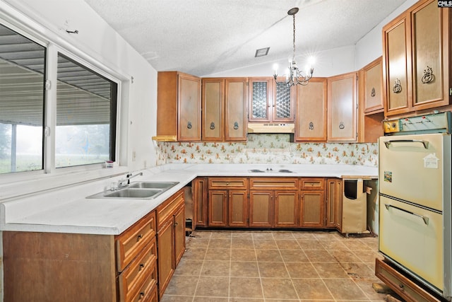 kitchen featuring decorative light fixtures, sink, light tile floors, and vaulted ceiling