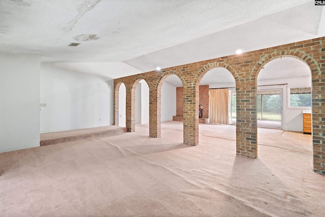 empty room featuring light colored carpet and brick wall