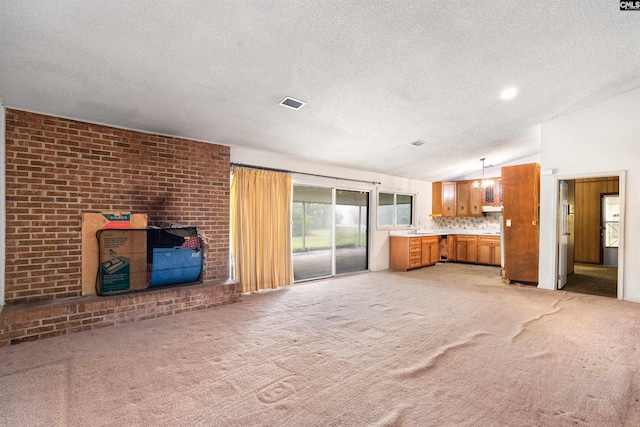 unfurnished living room with light colored carpet, vaulted ceiling, brick wall, and a textured ceiling