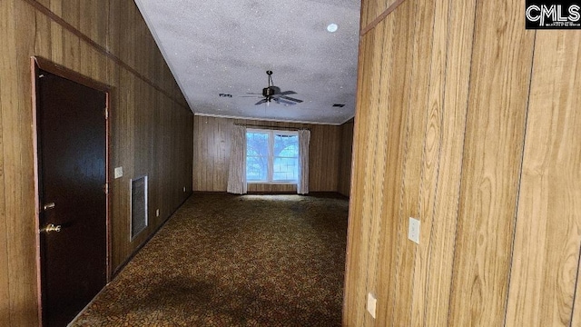 corridor with a textured ceiling, wood walls, and carpet flooring