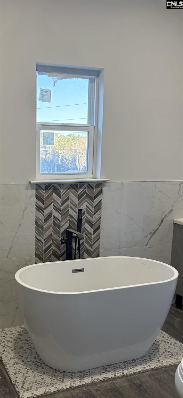 bathroom featuring a tub to relax in and tile walls