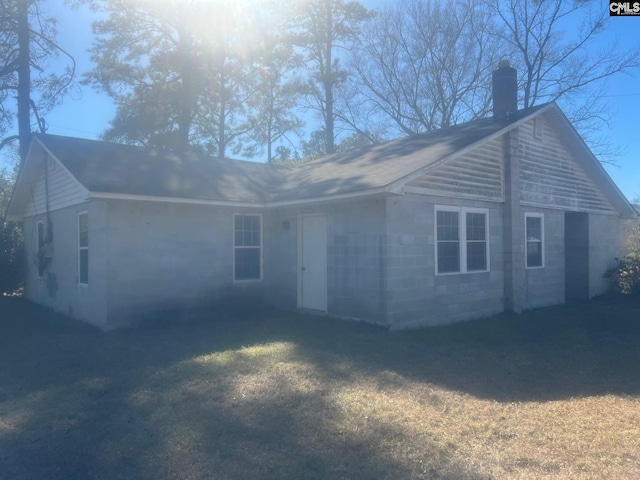 rear view of property with concrete block siding and a chimney