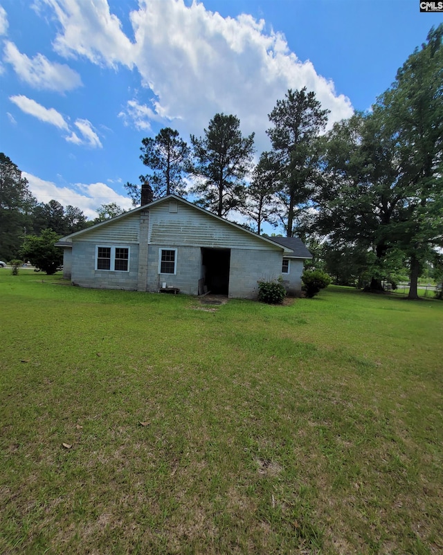 view of home's exterior featuring a lawn, concrete block siding, and a chimney