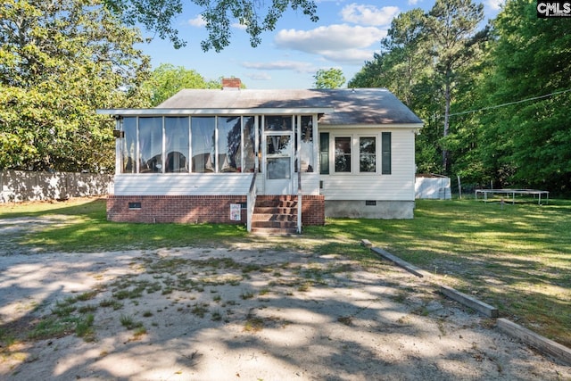 view of front of home featuring a trampoline, a sunroom, and a front yard