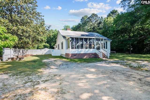 rear view of property featuring a yard and a sunroom