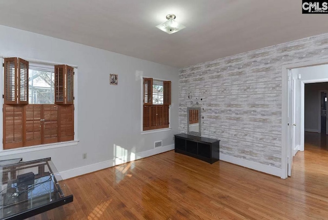 unfurnished living room featuring a wealth of natural light and hardwood / wood-style flooring