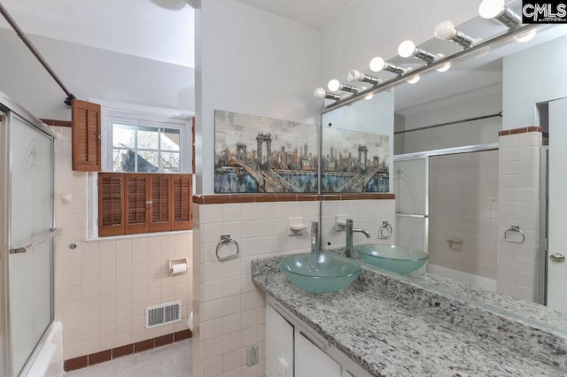 bathroom with enclosed tub / shower combo, tile walls, vanity, and tile floors