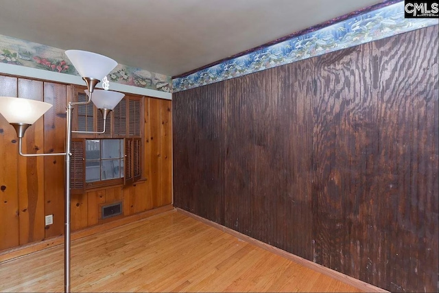 spare room with light hardwood / wood-style flooring and wooden walls