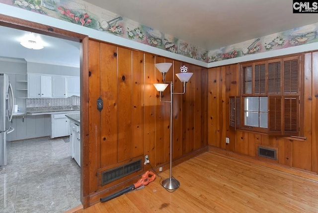 spare room with wooden walls and light wood-type flooring