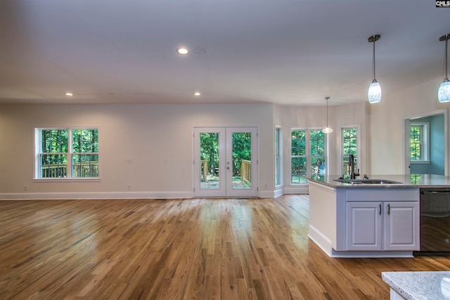 kitchen with pendant lighting, sink, black dishwasher, light hardwood / wood-style floors, and white cabinetry