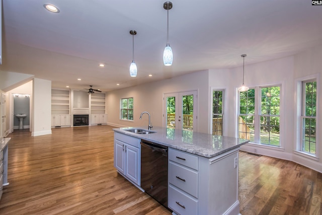 kitchen featuring light stone countertops, dishwasher, sink, an island with sink, and light hardwood / wood-style floors