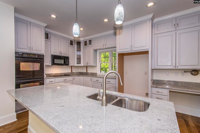 kitchen featuring pendant lighting, sink, light stone counters, and black appliances