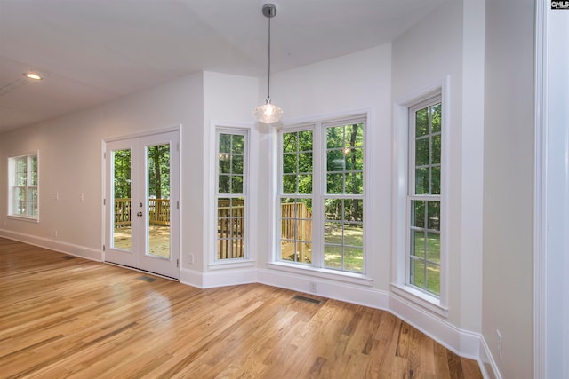 unfurnished dining area with french doors and light wood-type flooring