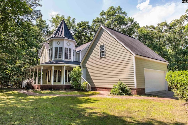 view of front of property with covered porch, a garage, and a front yard