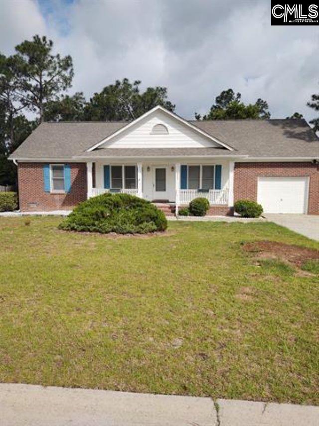 ranch-style home with a garage, a front lawn, and covered porch