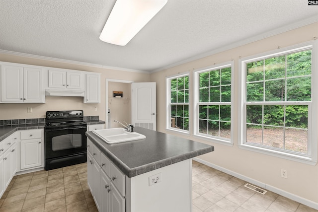 kitchen featuring under cabinet range hood, black range with electric stovetop, visible vents, dark countertops, and a center island with sink