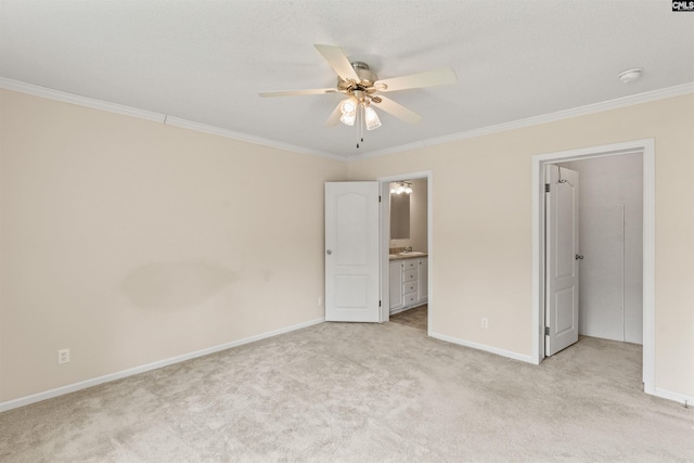 unfurnished bedroom with ceiling fan, ensuite bathroom, crown molding, and light colored carpet