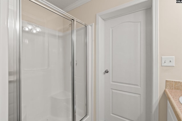 bathroom with crown molding, a textured ceiling, vanity, and a shower with shower door