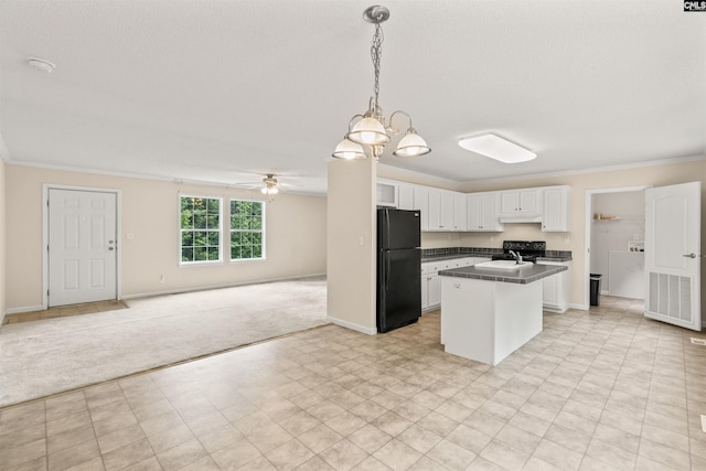 kitchen with white cabinets, open floor plan, hanging light fixtures, black appliances, and dark countertops