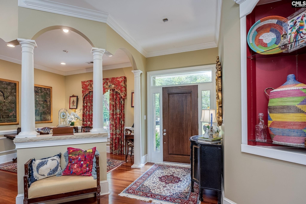 foyer entrance with crown molding, decorative columns, and hardwood / wood-style floors