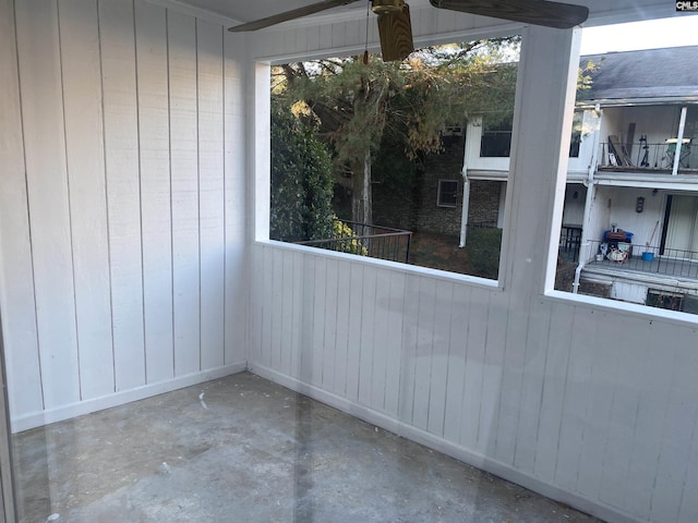 empty room with a healthy amount of sunlight, wood walls, and unfinished concrete floors