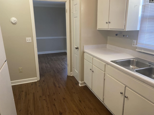 kitchen with a sink, baseboards, white cabinets, light countertops, and dark wood finished floors