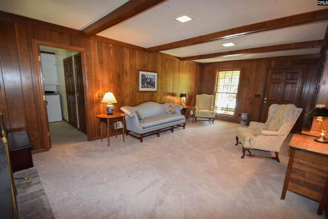 living area featuring wooden walls, beam ceiling, washer / dryer, and light carpet