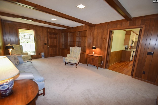 carpeted living room featuring beamed ceiling and wooden walls