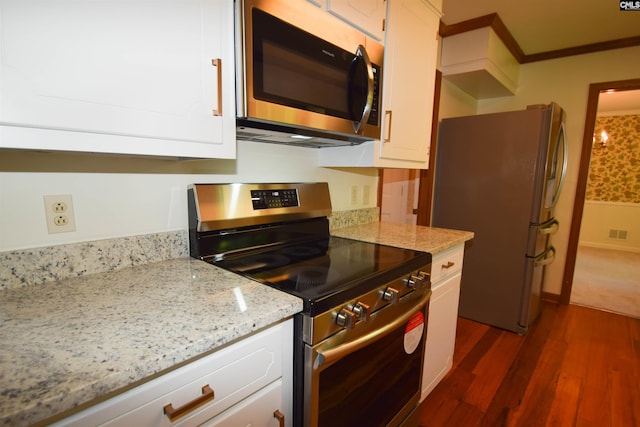 kitchen with white cabinets, stainless steel appliances, crown molding, light stone countertops, and dark wood-type flooring