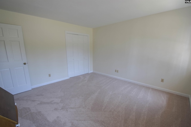 unfurnished bedroom featuring light colored carpet and a closet