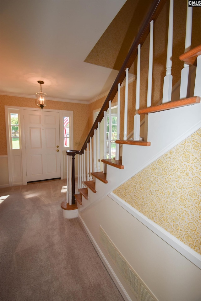 foyer with crown molding and carpet flooring