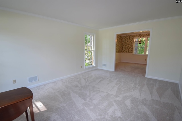 spare room featuring ornamental molding, light carpet, and a notable chandelier