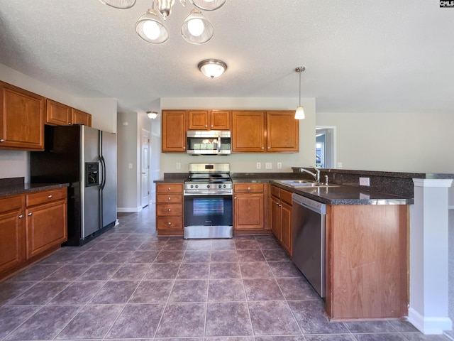 kitchen featuring appliances with stainless steel finishes, a textured ceiling, dark tile patterned floors, sink, and pendant lighting