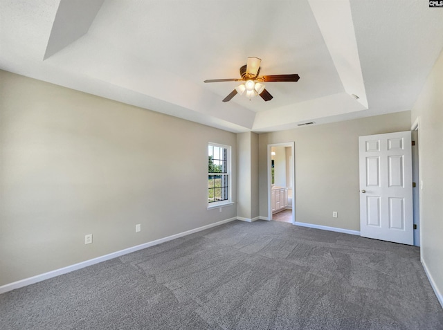 spare room featuring carpet, ceiling fan, and a tray ceiling