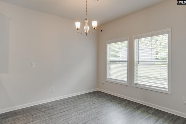 unfurnished room with light hardwood / wood-style floors and an inviting chandelier