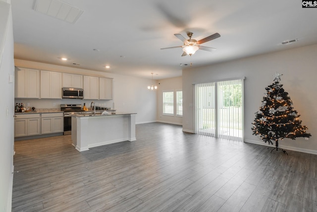 kitchen featuring hardwood / wood-style floors, a center island with sink, white cabinets, ceiling fan with notable chandelier, and appliances with stainless steel finishes