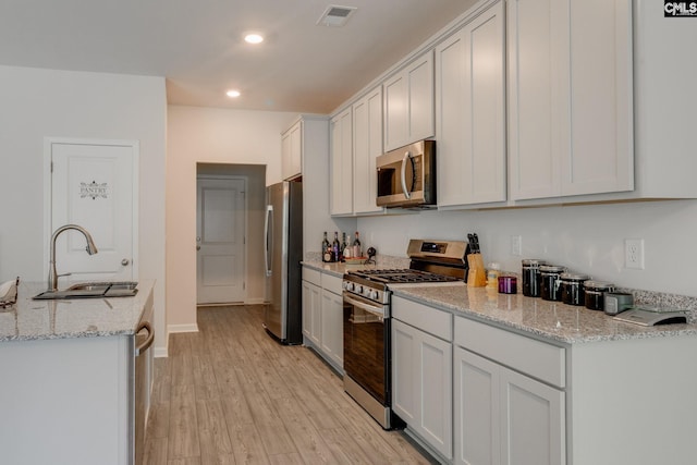 kitchen featuring white cabinetry, light hardwood / wood-style flooring, sink, and appliances with stainless steel finishes